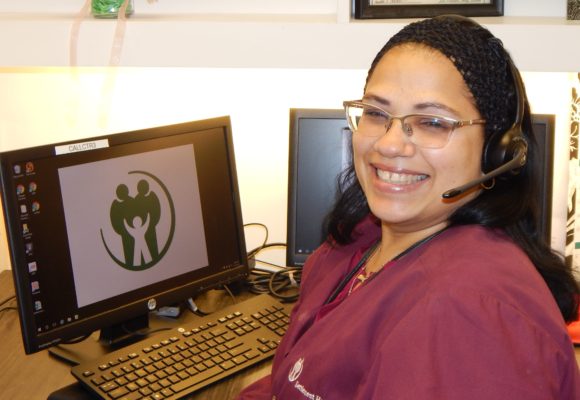 female customer service agent smiling in front of computer with headset