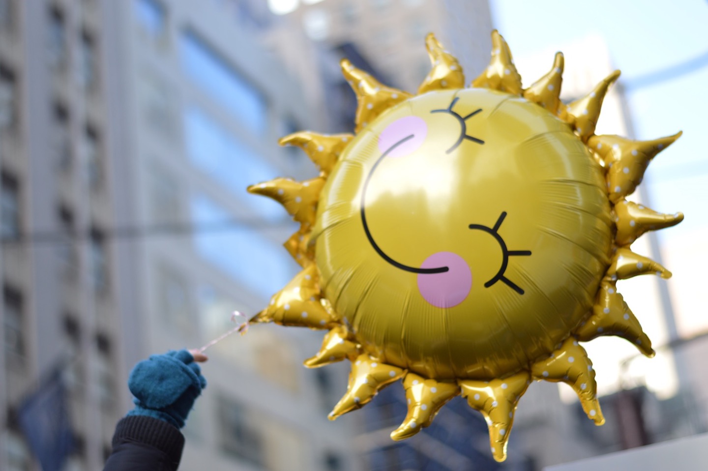 A hand holds a sun-shaped balloon.