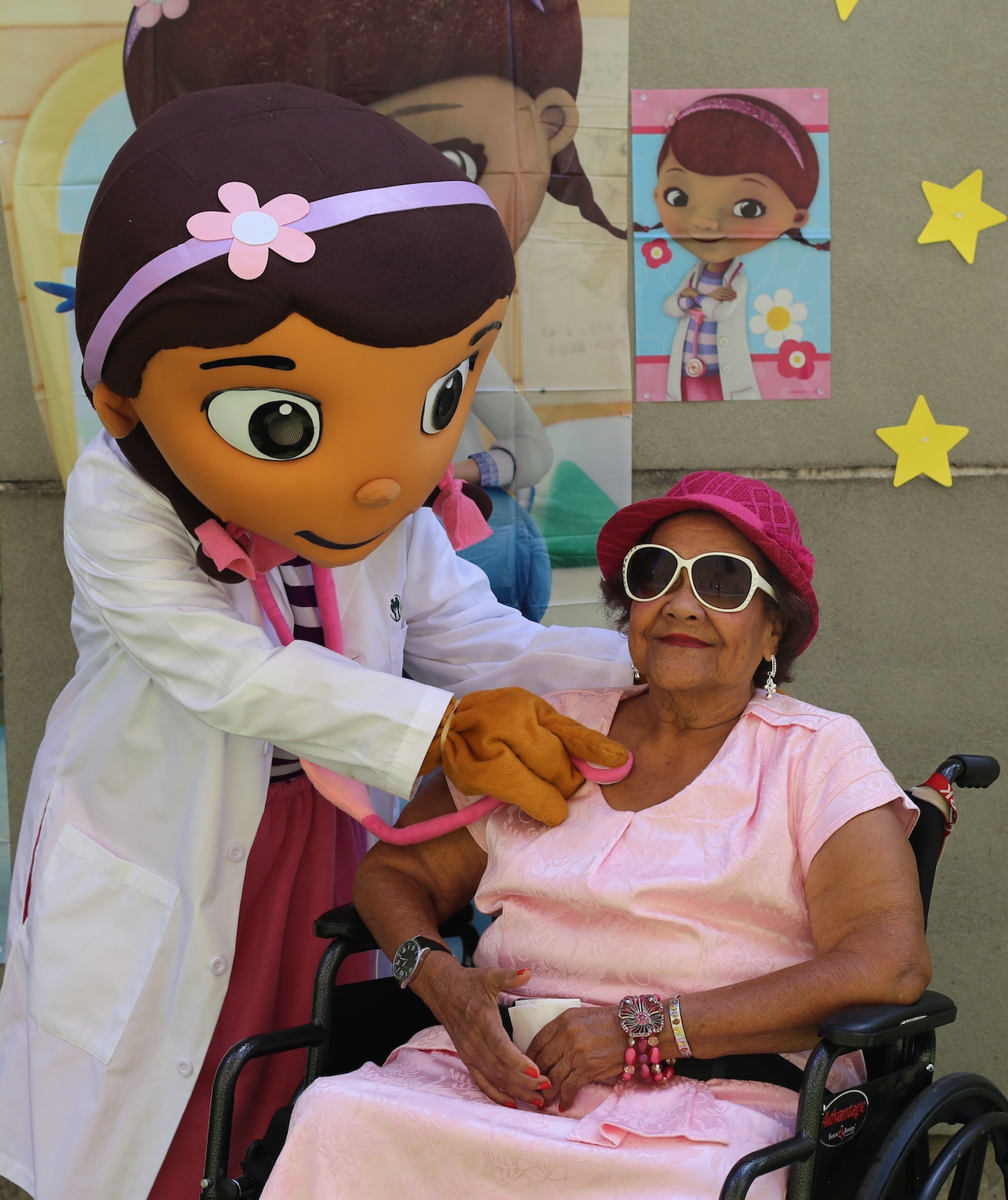 A costumed "doctor" uses a stethoscope as an older patient in a wheelchair plays along.